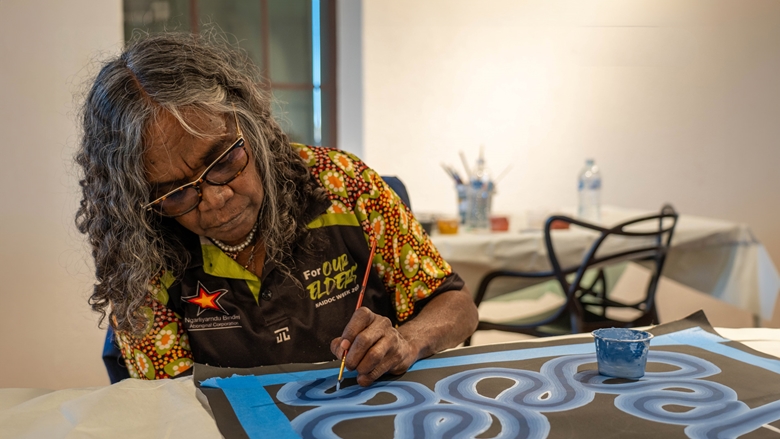 Signature Artist Yindjibarndi woman Wendy painting one of her artwork. 