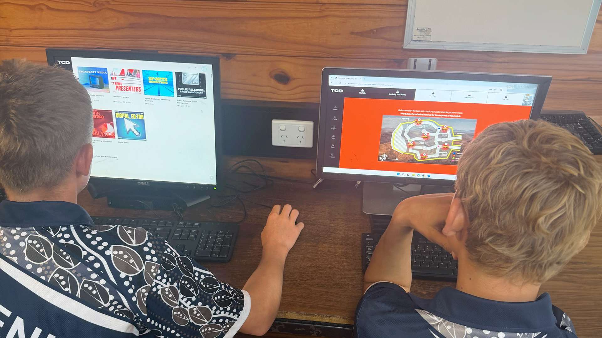 Two young students looking at the desktop monitor screen