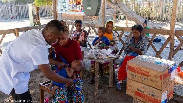 Mother holding her child while health care worker is screening the child's health for malnutrition. 