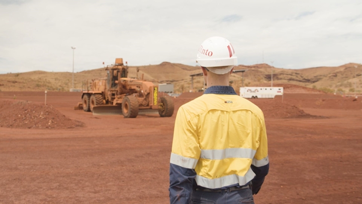 A Rio Tinto employee walking toward a vehicle at a mining site.