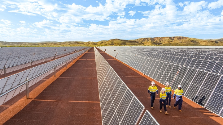 Four people walking through Gudai Darri solar farm