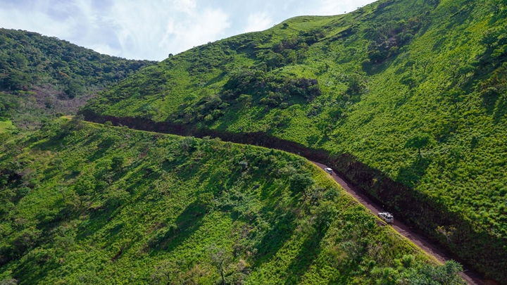 Aerial photo of vehicles driving on dirt road towards Pic de Fon from Canga East Camp, Simandou, Guinea