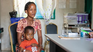 A mother holding her son while visiting a community clinic.