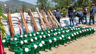 A group of people working together to organise shovels, seeds, and watering tools.
