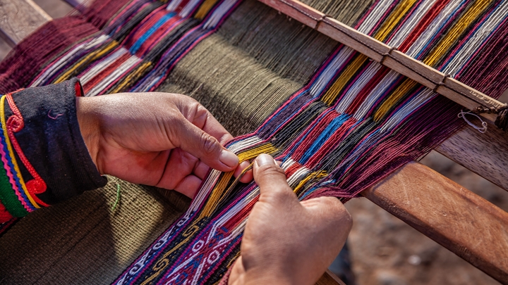 Woman weaving colourful threads, Peru