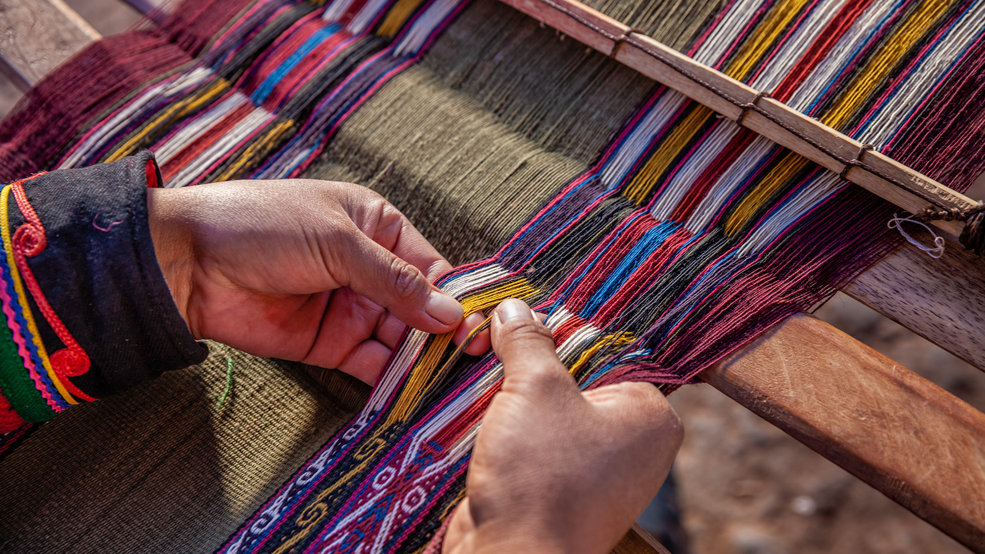 Woman weaving colourful threads, Peru