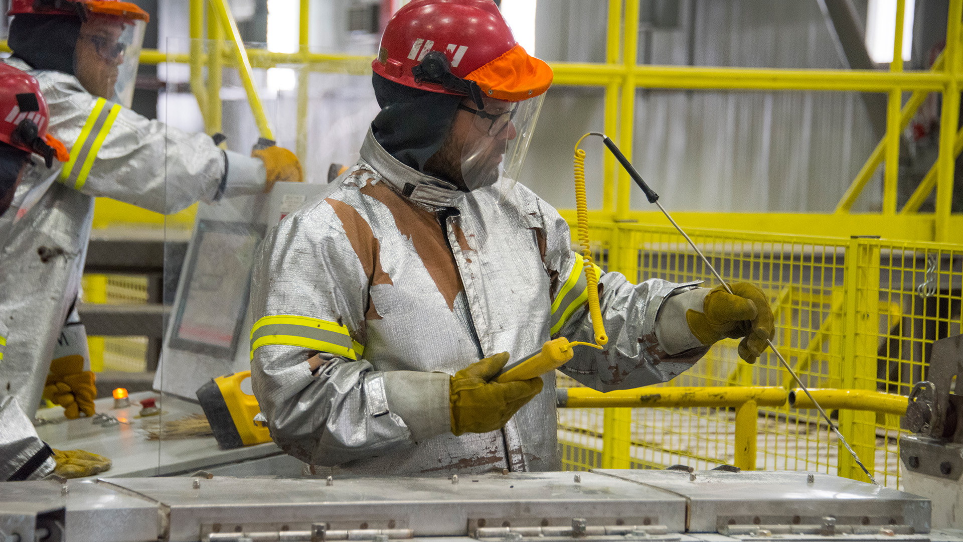 Employees check the temperature of molten aluminium going into the straight-line casting machine at Kitimat