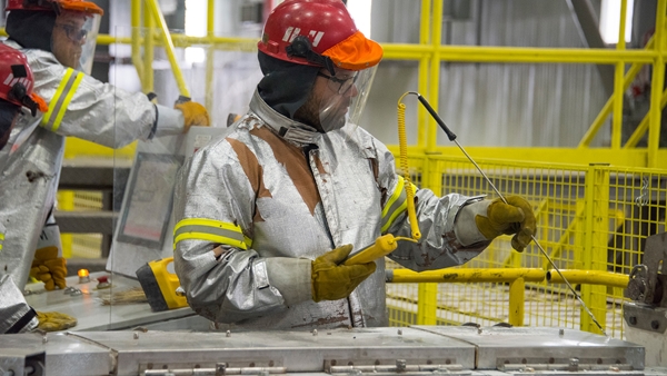 Employees check the temperature of molten aluminium going into the straight-line casting machine at Kitimat