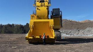 Julia a graduate from Labrador standing in front of a yellow mining truck.